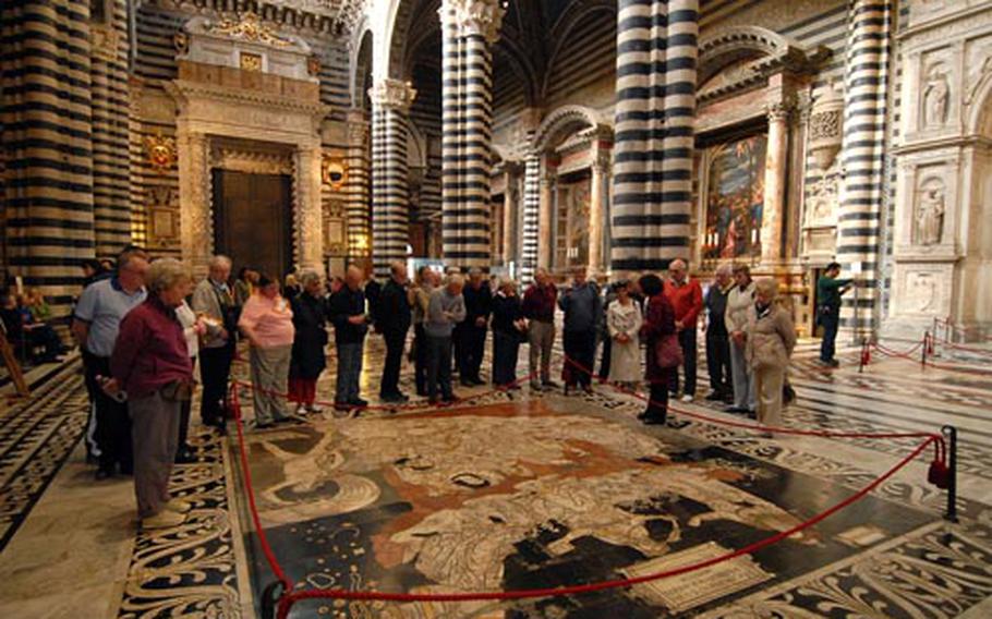 A tour group views one of the 59 marble panels on the floor of the Siena cathedral. Note the ornate decorations and the alternating dark and light bands of marble.