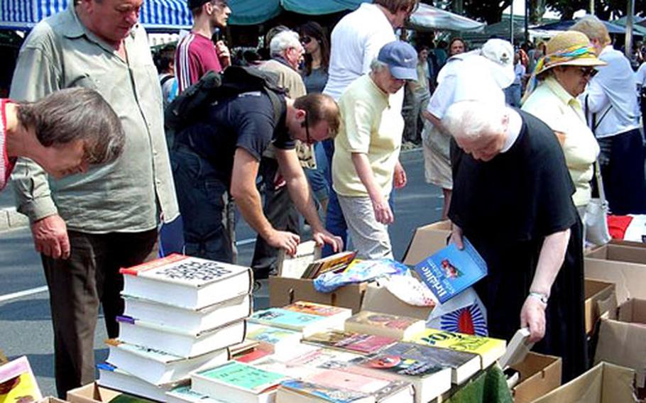 Shoppers browse through a pile of books, looking for bargains at a flea market in Frankfurt, Germany.