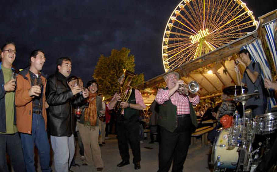 Participants in the festival sway and sing in unison to a traditional German band during the opening night.