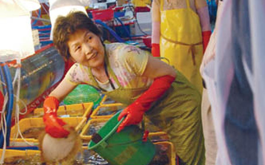 A worker at the Jagalchi fish market picks out live seafood for a customer. Customers buy live fish and have it killed before leaving the market.