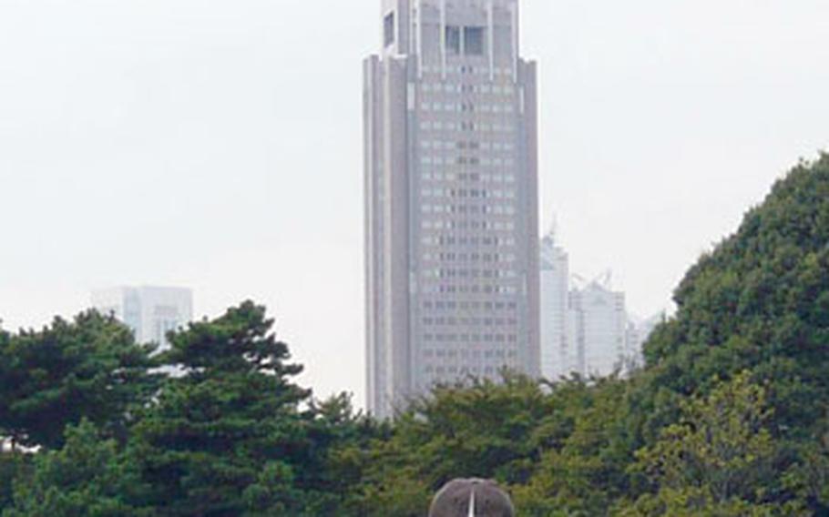 Visitors relax on a fall Saturday at Shinjuku Gyoen National Park. In the background is the Japanese mobile company NTT Docomo&#39;s building in Shinjuku.