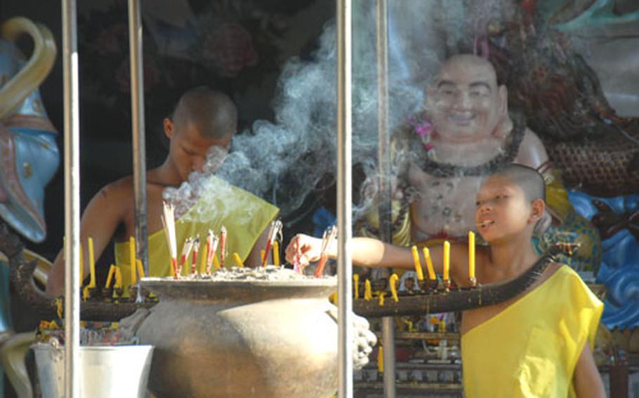 Two young monks light incense outside at wat in Chiang Mai.