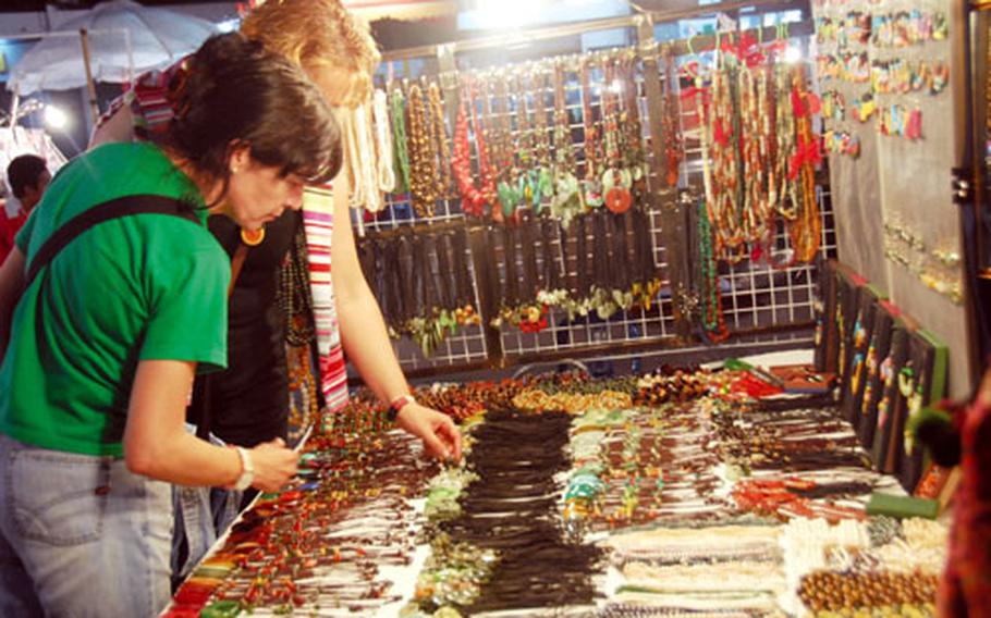 Shoppers look at jewelry at a stall in Chiang Mai&#39;s Night Bazaar, one of the city&#39;s main tourist attractions. Hundreds of vendors sell everything from tapestries to clothing at the bazaar, which runs from dusk till midnight.