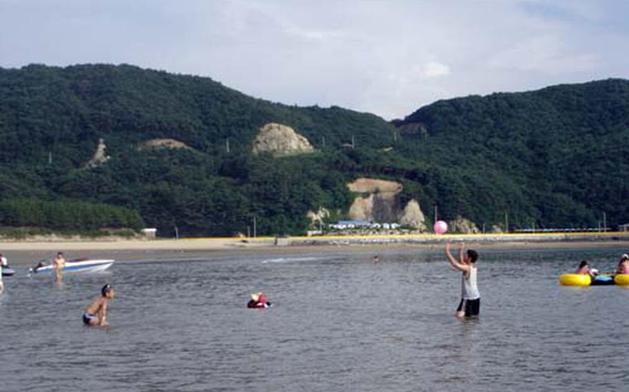 Beachgoers relax at Seopori Beach on Deokjeokdo. The beach, the most popular on the small island, includes concessions and small pine forest.