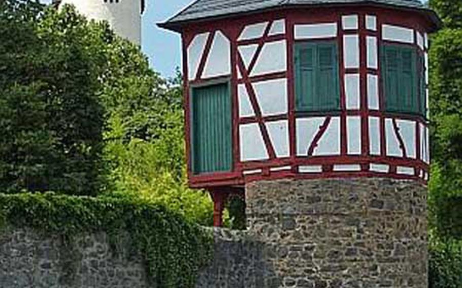 A bicyclist rides on the path that runs along the Main River, past Steinheim’s castle keep at left, and the old toll tower.