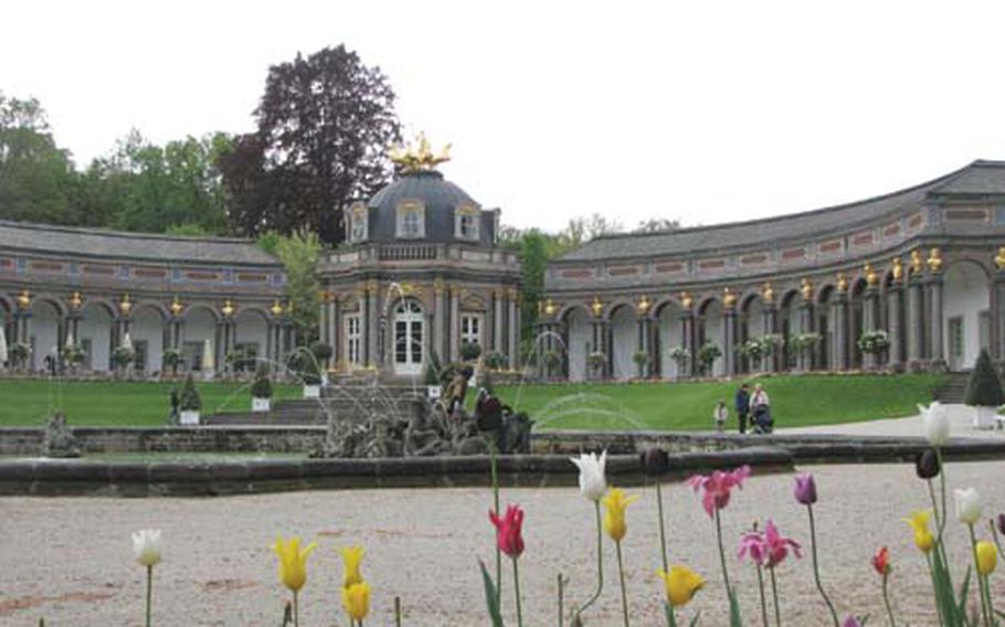 A golden statue of Apollo, the Greek god of art and music, crowns the Sun Temple at the Hermitage on the outskirts of Bayreuth, Germany. The front of the building is covered with thousands of small stones, like a mosaic.