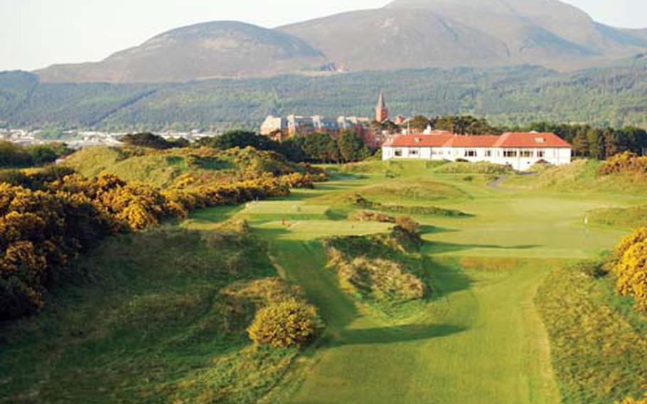 A view of Northern Ireland’s Royal County Down Golf Club, clubhouse in foreground, looking toward the Mourne Mountains and the Slieve Donard Hotel (with steeple).