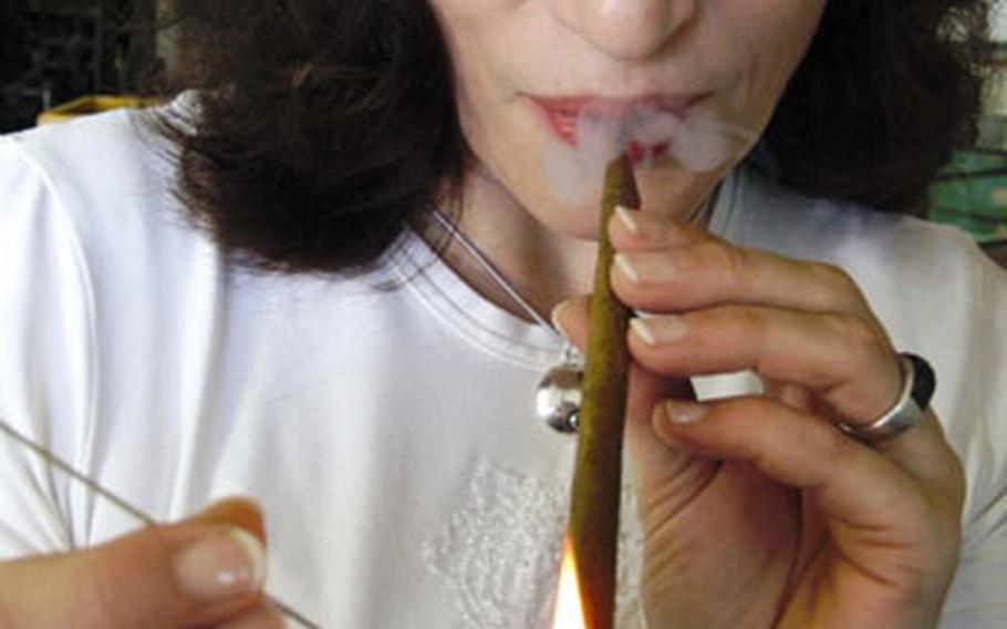 Cornelia Stix, head of the cigar company, lights one of the products of the family business.