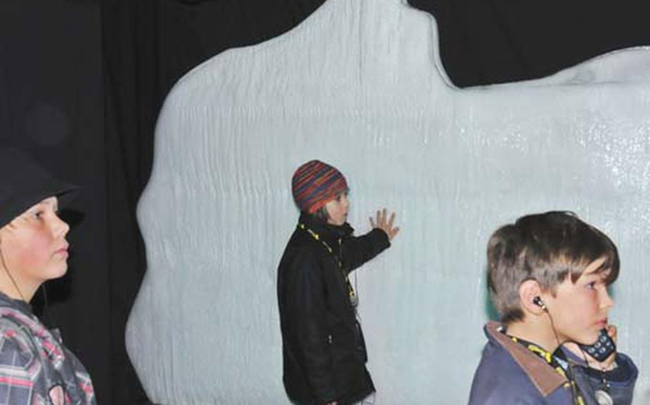 A group of young visitors listens to a lecture about icebergs in front of an artificial iceberg at the Titanic exhibit. As they touch the iceberg, they learn about the icy temperatures of the sea at the time of the disaster.