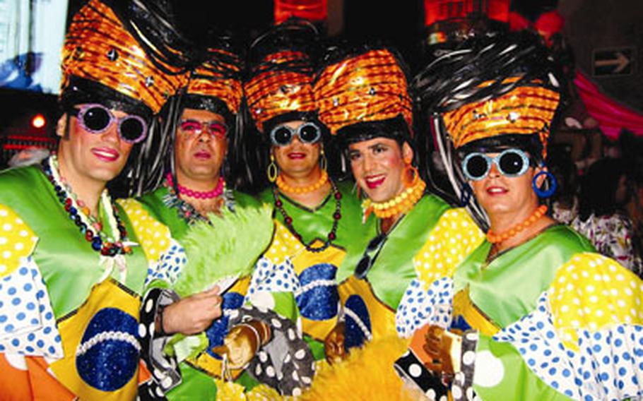 Gaily dressed performers take a break from one of Las Palmas’ wild street parties, known as “Mogollons,” to pose for a photo during the island’s carnival celebration.