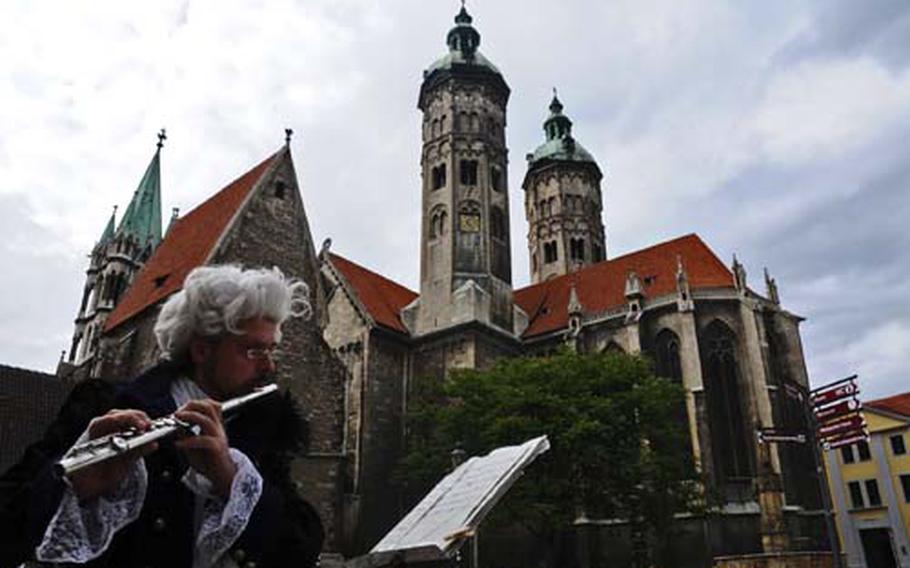 A musician in historical costume plays classical tunes on his flute in front of Sts. Peter and Paul, NaumburgÕs cathedral.