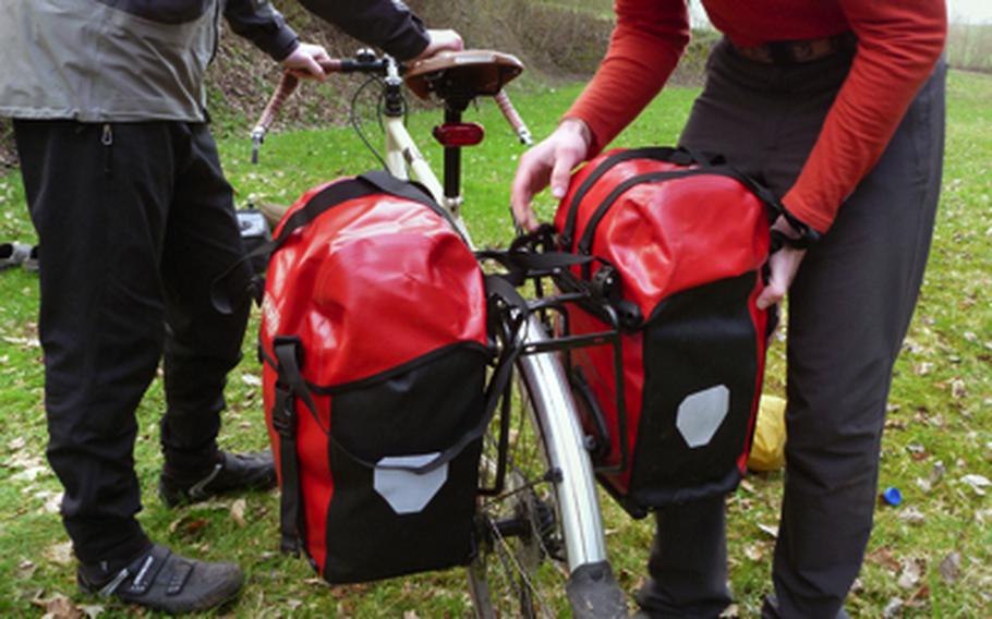 Luke Stover attaches a waterproof pannier to his bike rack after a night of camping at a site near Schönenberg-Kübelberg in Germany.  A rear bike rack and panniers are the nuts and bolts of carrying gear on a bike tour.