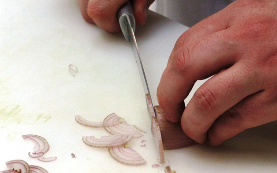 The proper way to slice a shallot or onion as demonstrated at one of the L'atelier des Chefs course - bend the fingers back to avoid cutting yourself.