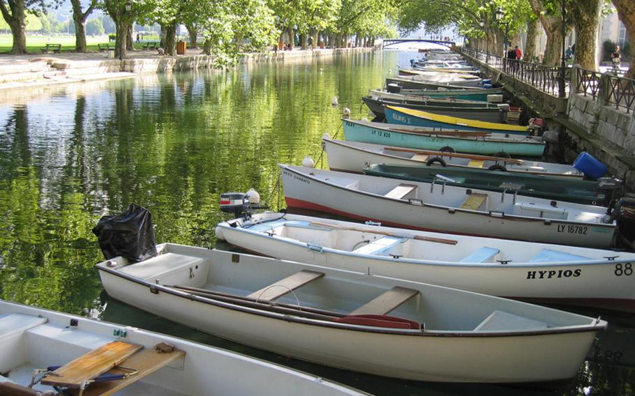 A row of boats lines a pristine, tree-lined canal in Annecy. The town's canals, lake and the surrounding mountains draw outdoors enthusiasts year round.