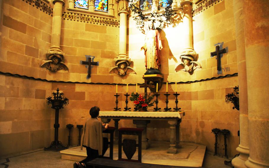 A woman kneels in prayer in La Sagrada Familia. 