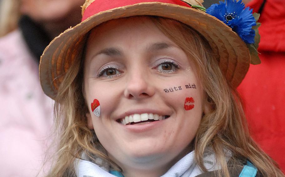 With the words "Bütz mich," Cologne slang for "kiss me" written on her cheek, a young lady enjoys the Cologne, Germany, Rose Monday parade. "Butzjer" are kisses made with pursed lips and have nothing in common with a real kiss.