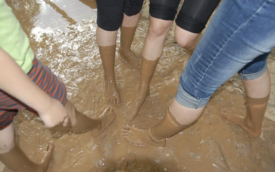 Visitors to the barefoot park show off their muddy feet and legs after walking through the cool mud basin.