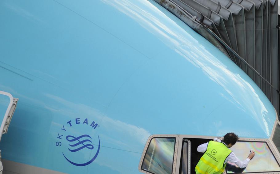 A member of the ground crew at Frankfurt Airport cleans the cockpit windshield of a Korean Air jet.