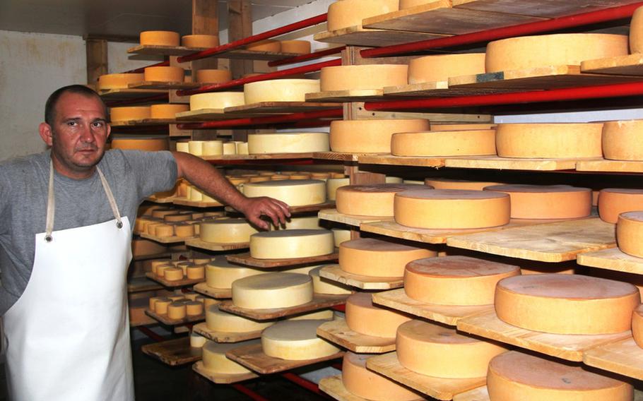 Carlo Ambrosini, a cheese maker at the Gerschnialp dairy farm, stands beside rounds of cheeses aging on the farm's shelves. The longer the cheese ages, the stronger the taste.  
