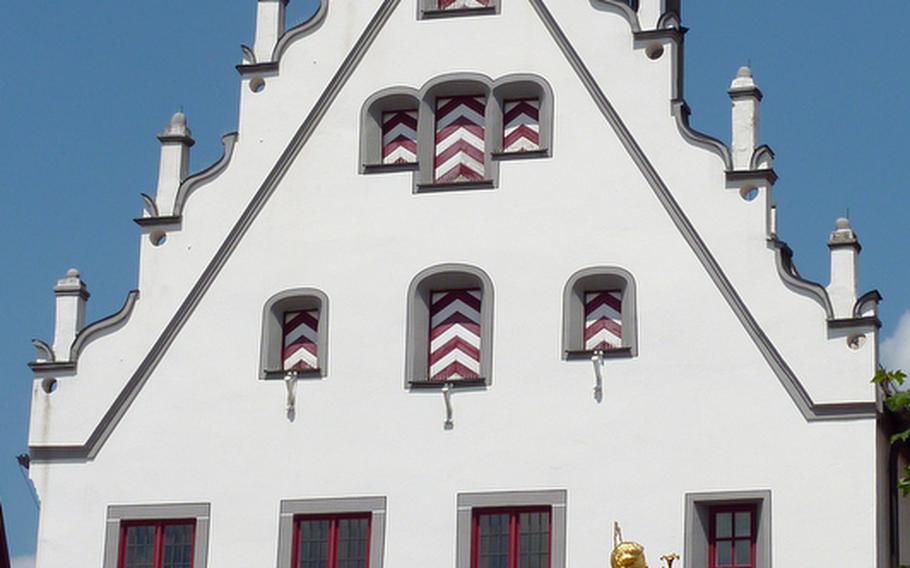 The Marktplatz in Wemding, Germany, is surrounded by many grand old buildings, such as the historical Rathaus (town hall). The golden Madonna statue stands in the center of the market square.