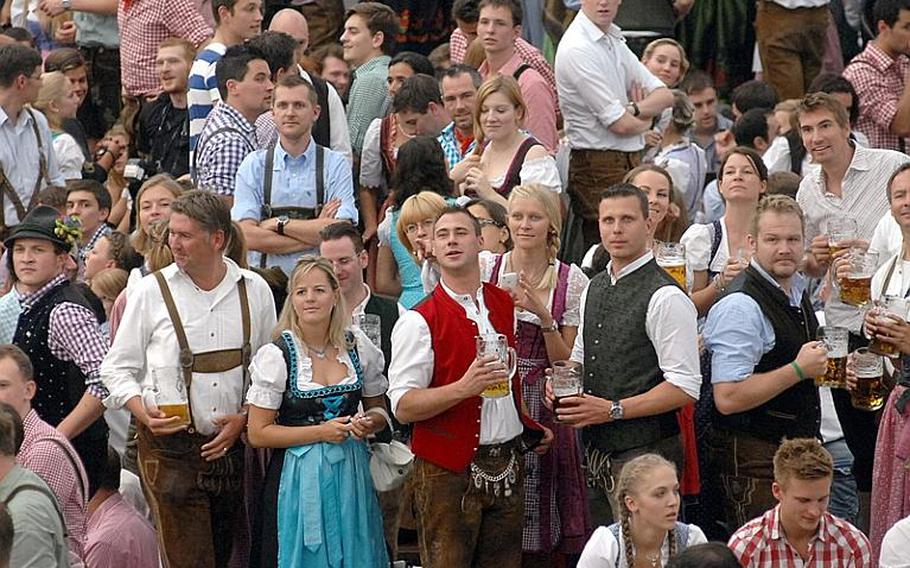 Oktoberfest tents are full on opening day with people in traditional Bavarian dress who are ready for a party.
