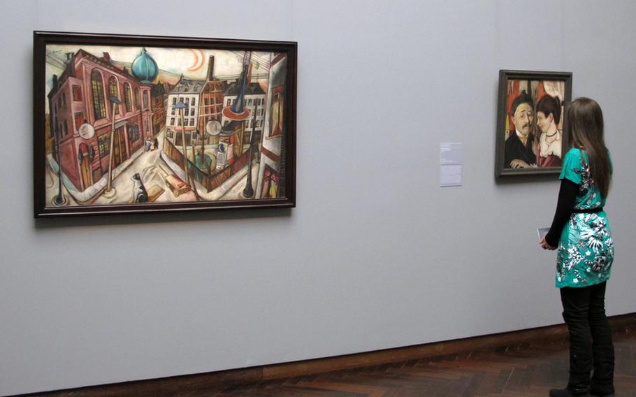 A visitor to the Städel modern art collection in Frankfurt, Germany, looks at Max Beckmann's "Portrait of the Carls." At left is his "Synagogue in Frankfurt am Main," one of his most famous paintings.