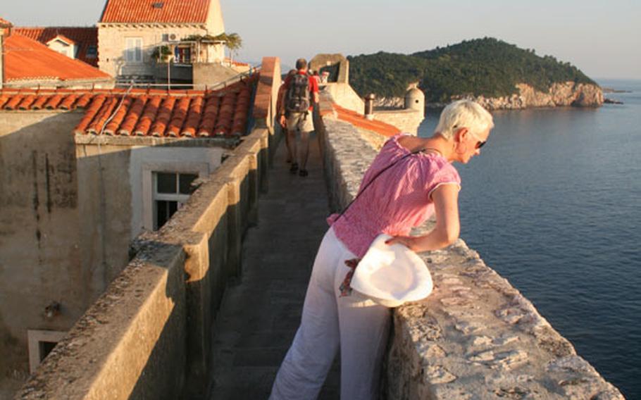 A woman looks over the edge of Dubrovnik's famous ramparts on a sunny day in the Croatian city. 