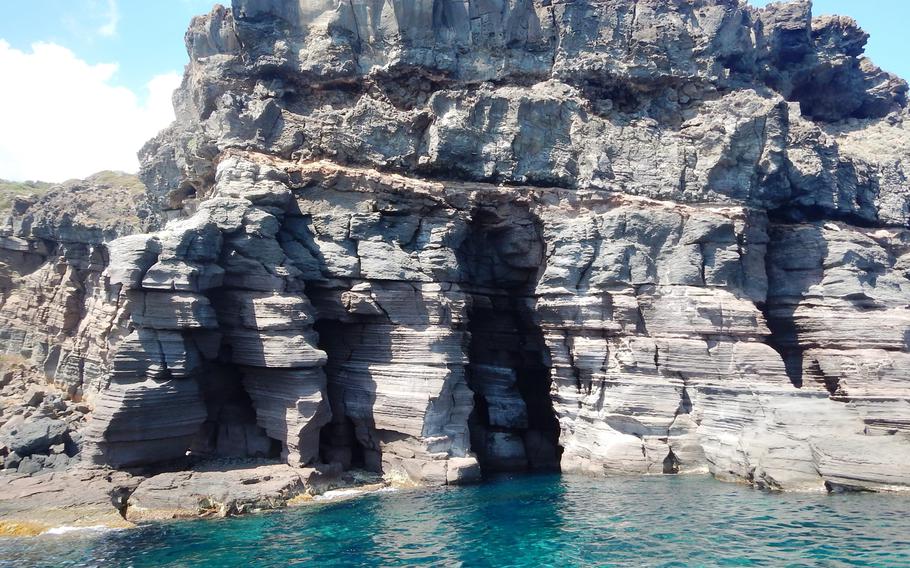 Unspoiled crystal-clear blue-green sea waters beckon visitors to the volcanic Italian island of Pantelleria, distinguished by several rock formations.