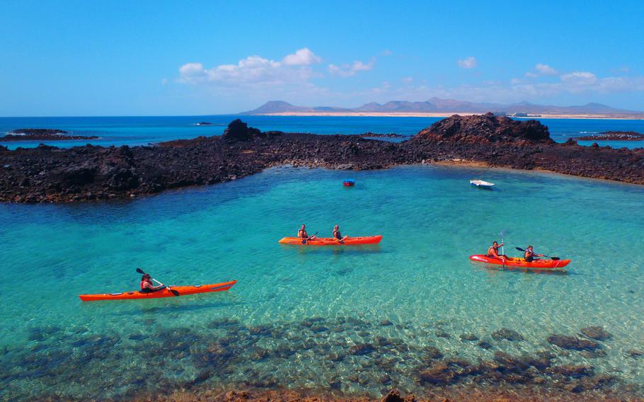 Sunshine and crystal-blue waters invite kayakers to the island of Fuerteventura, in the Canary Islands.