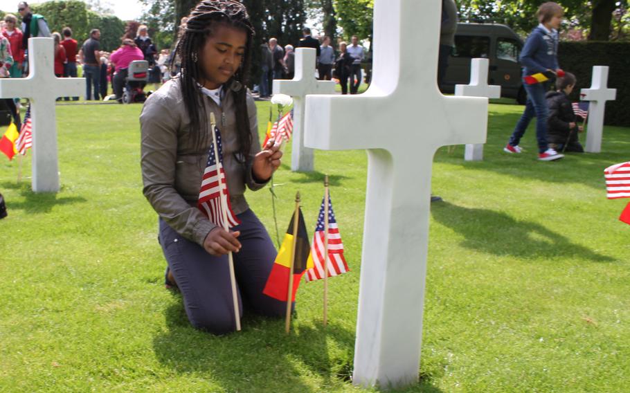 A student from Waregem, Belgium, places flags on the graves at Flanders Field American Cemetery.