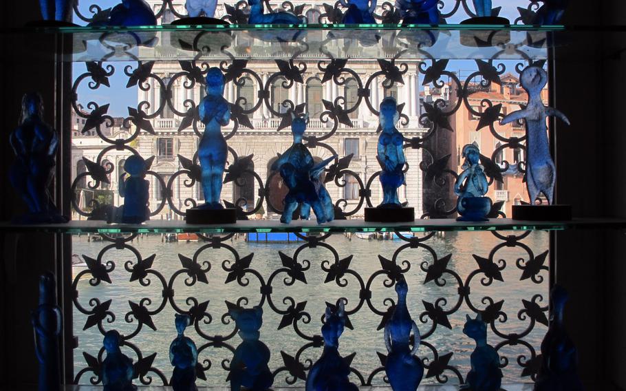 Blue glass sculptures created by Egidio Costantini, inspired by Picasso, are displayed in a window of the Peggy Guggenheim Collection overlooking the Grand Canal in Venice.