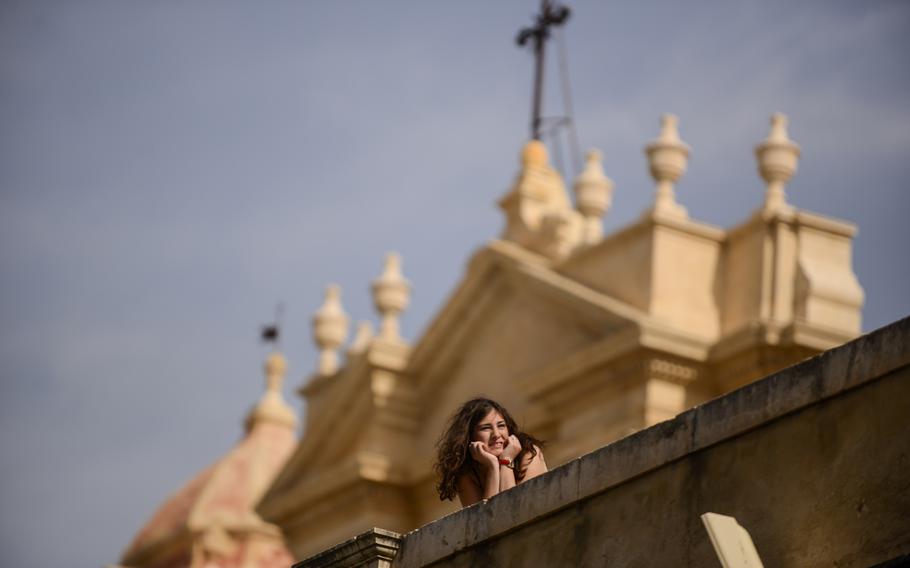 A woman looks down Noto's main street with the Noto Cathedral in the background in Noto, Sicily.