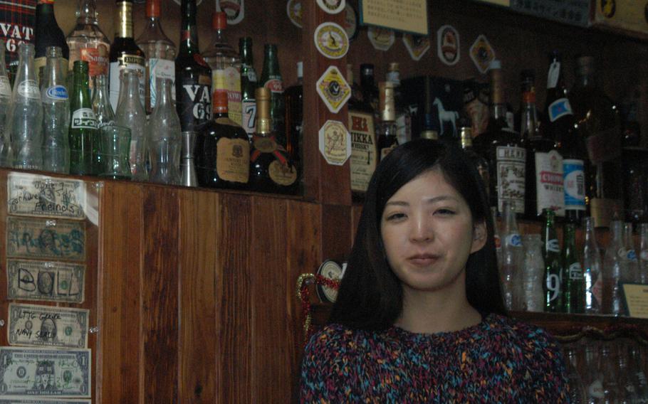 Asaka Sone, a staffer at The Okinawa Gallery of Culture and History, stands behind the counter of a replica of a typical bar that catered to U.S. servicemembers in the '50s through the '70s. 