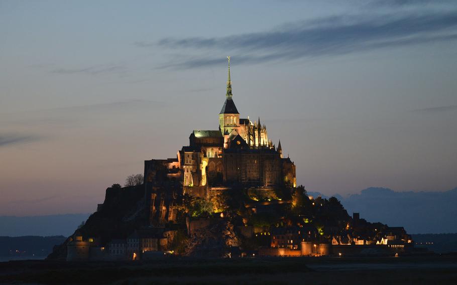 Mont-St-Michel at dusk. The first church built on this small island off the French coast was constructed in 709. Later, an abbey church was built on the top of the rock and fortifications were added. Today it is one of France's top tourist attractions.