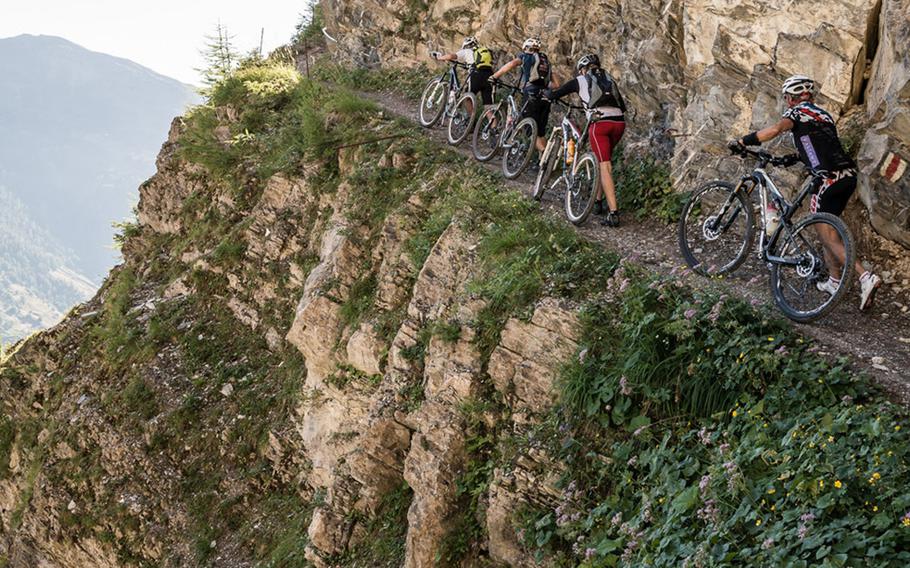 Bikers push their bikes up a steep trail in the mountains around Leukerbad, Switzerland.