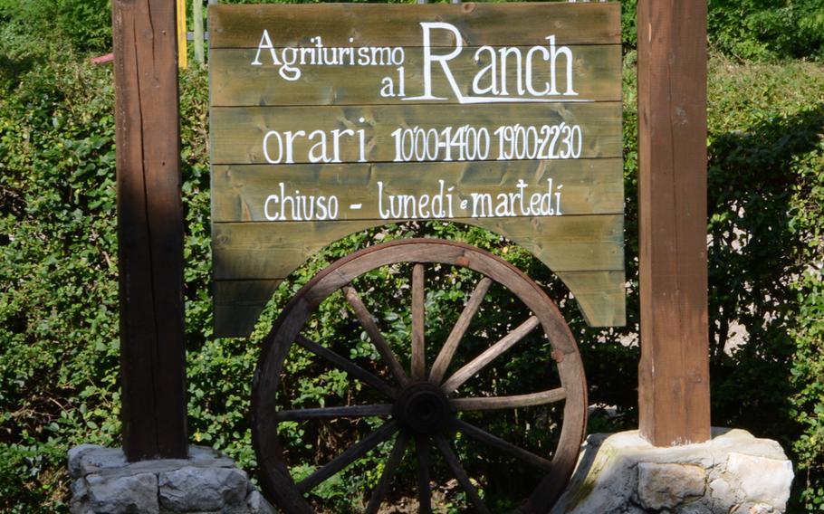 A sign posting the operating hours at Agriturismo al Ranch i sits a few meters away from the entrance to the saloon.  