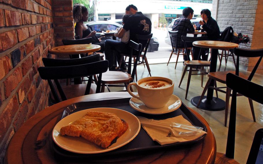 Customers sip coffee and eat freshly made breads and pastries at Bread Show, a French-style bakery and cafe in Itaewon. In the foreground are a cappuccino and a pastry with a lemon-flavored filling.