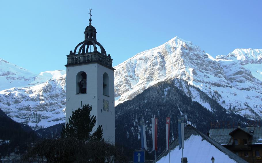 Mountain peaks rise above the bell tower of a church in Champ?ry, Switzerland.