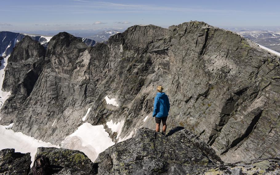 A Norwegian woman takes in views of snow and mountain peaks in Dovrefjell National Park, Norway.