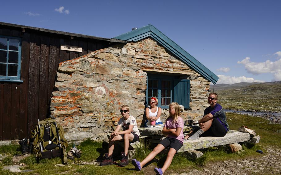A Norwegian family enjoys the scenery outside the Amotsdalshytta hut in Dovrefjell National Park, Norway.