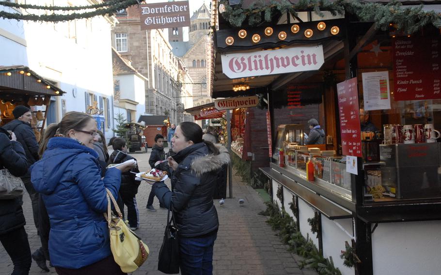 Women chat at the Speyer Christmas Market in December 2013, while one enjoys a warm waffle topped with whipped cream and fruit.