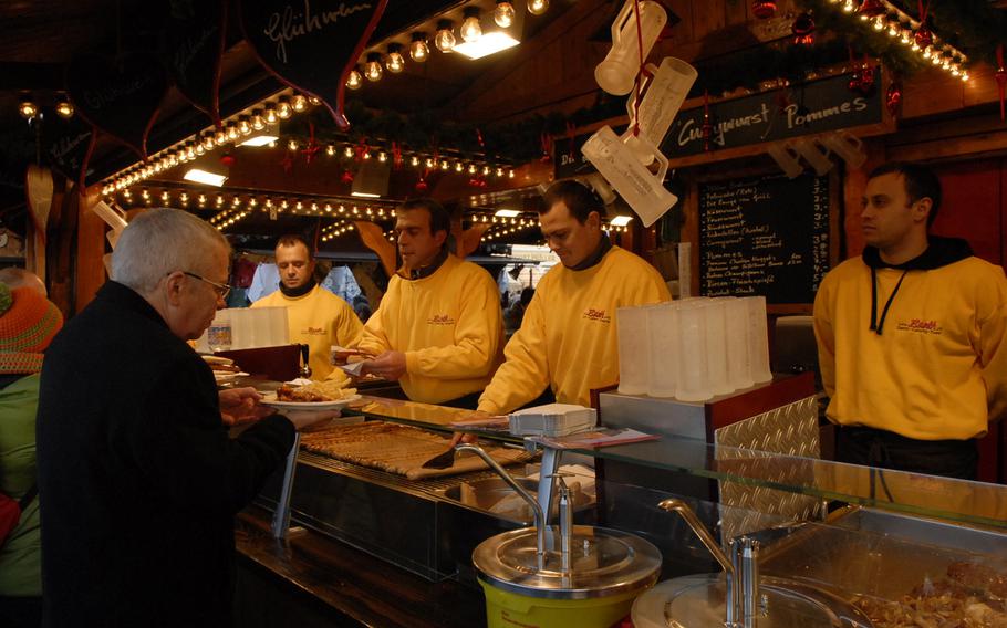 Men in yellow serve up red and white bratwurst at the Speyer Christmas Market in Speyer, Germany, in December 2013. Eating is a popular activity at the market, where vendors sell Palatinate delicacies such as potato soup and yeast dumplings.