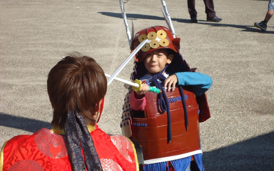 A child in a samurai costume wages a swordfight duel with a re-enactor at Osaka Castle.