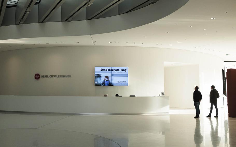Visitors to the World of Leica, the Leica manufacturing and administrative complex, view pictures and event advertisements in the reception hall.