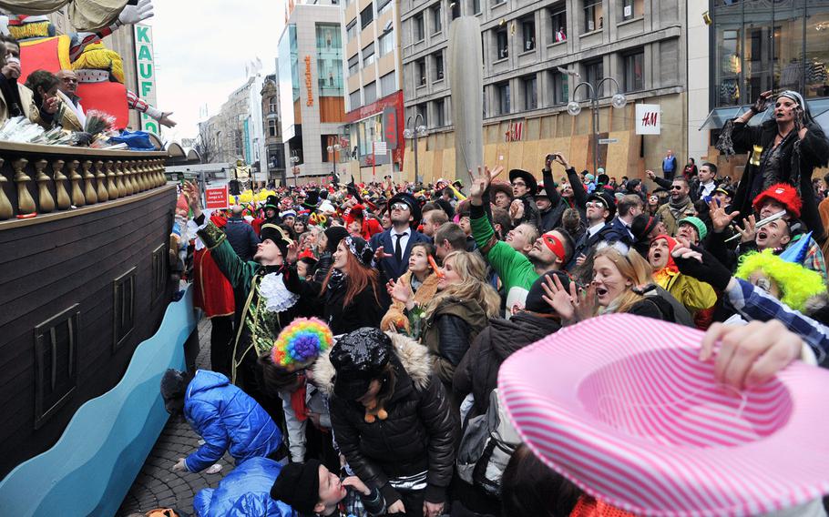 Spectators try to catch candy thrown from a float at the 2014 Cologne Rose Monday parade. Hundreds of thousands of people line the street for the annual event, the highlight of the city's Carnival celebration.  