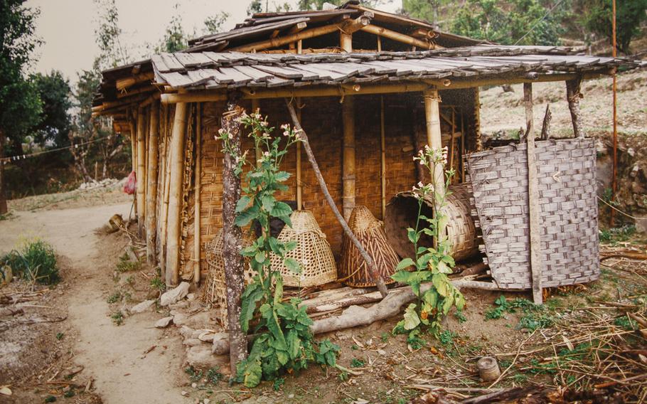 A photo on display of a traditional home of the Rai minority people with walls made of woven bamboo and wooden shakes for the roof.