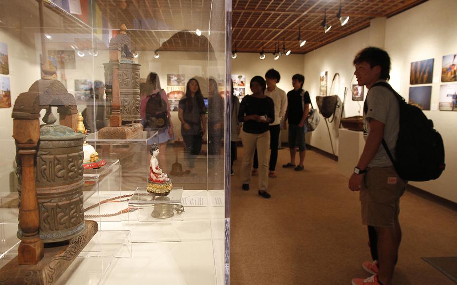 A group of Japanese tourists views the exhibits at "Mountain Minorities: Tamang and Rai Cultures of Nepal" at the East-West Center Gallery in Honolulu. The items in the glass case are used for religious practices.