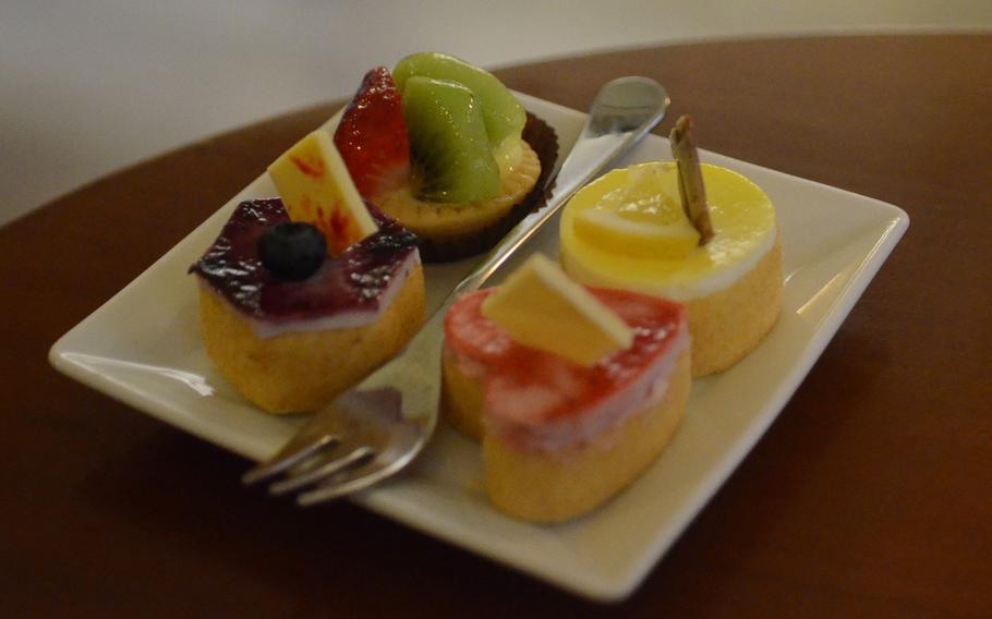 A blueberry mousse, strawberry heart-shaped mousse and lemon mousse accompany a strawberry and kiwi mini pie on a plate at Peratoner.
