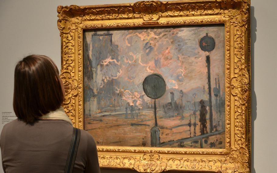 A visitor to the "Monet and the Birth of Impressionism" exhibit at the Städel in Frankfurt, Germany, looks at Claude Monet's "Exterior of Saint-Lazare Station (the Signal)" from 1877.