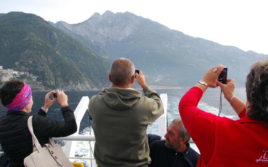 Passengers on a boat tour along the shore of Mount Athos snap photos of one of the 20 monasteries on the peninsula. Boats carrying women must stay about a third of a mile from shore.